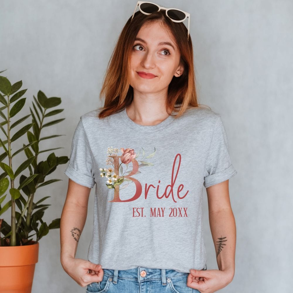 Customizable floral bride shirt for fiancée, wife, spouse, BFF or bestie on your wedding or anniversary. Great idea for engagement announcement, bachelorette party, bridesmaid gift idea, rehearsal dinner outfit, and after wedding party gift. This cute getting ready casual tee is a perfect idea for soon-to-be daughter-in-law, future Mrs. bride or as a honeymoon vacation souvenir. Personalize with date for a special touch.