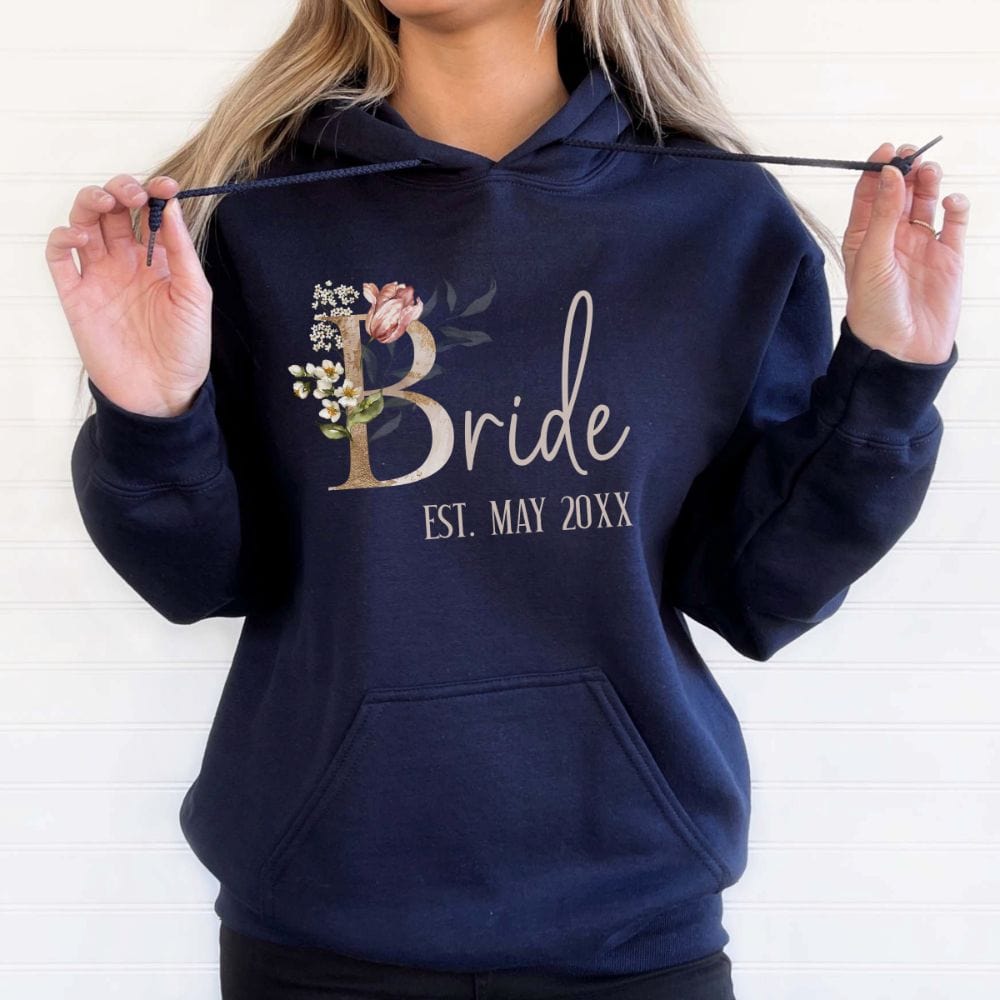 Customizable floral bride hoodie for fiancée, wife, spouse, BFF or bestie on your wedding or anniversary. Great idea for engagement announcement, bachelorette party, bridesmaid proposal box gift idea, rehearsal dinner, and after wedding party. This cute getting ready present is a perfect idea for soon-to-be daughter-in-law, future Mrs. bride or as a honeymoon vacation souvenir. Personalize with date for a special touch.