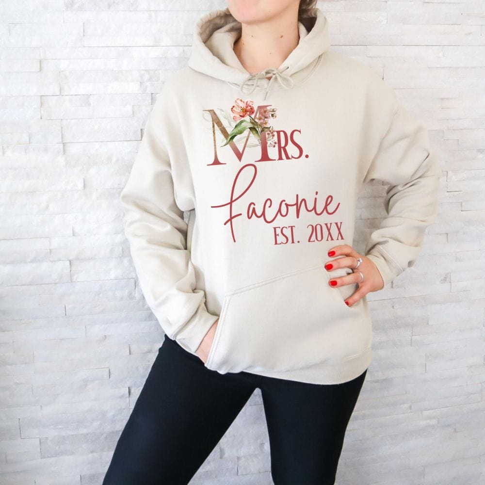 Customizable floral Mrs hoodie for fiancée, wife, spouse, BFF or bestie on your wedding or anniversary. Great idea for engagement announcement, bachelorette party, bridesmaid proposal box gift idea, rehearsal dinner, and after wedding party. This cute getting ready present is a perfect idea for soon-to-be daughter-in-law, future Mrs. bride or as a honeymoon vacation souvenir. Personalize with name and date for a special touch.